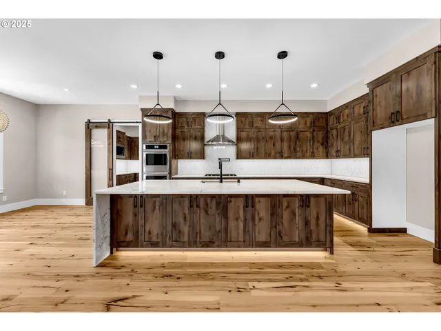 a view of kitchen with kitchen island stainless steel appliances cabinets and wooden floor