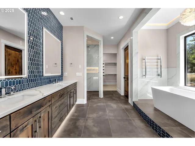 a large bathroom with a double vanity sink a large mirror and a bathtub