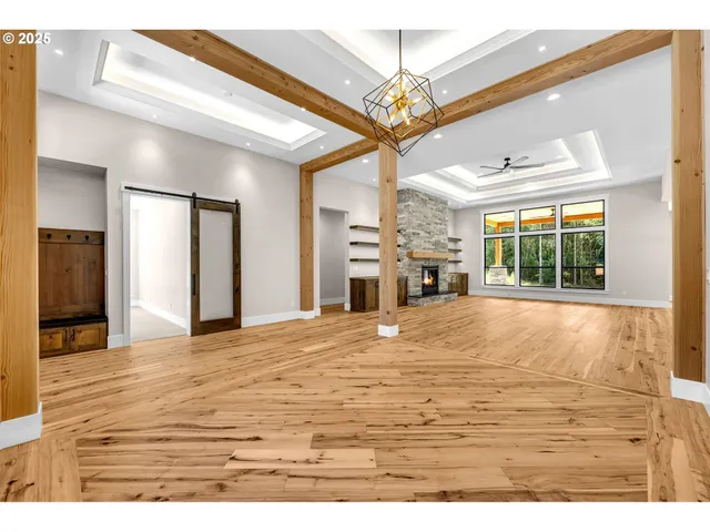 a view of an empty room with wooden floor and chandelier
