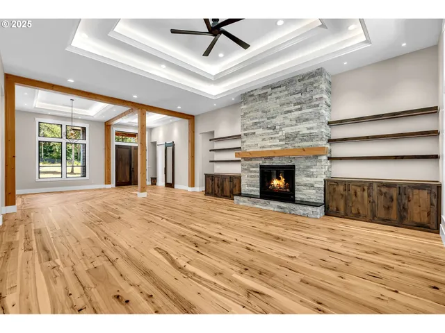 a view of an empty room with wooden floor fireplace and a window