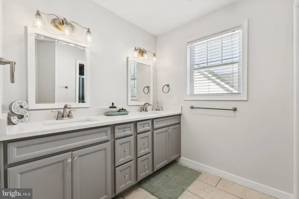 a bathroom with a double vanity sink a mirror and a window