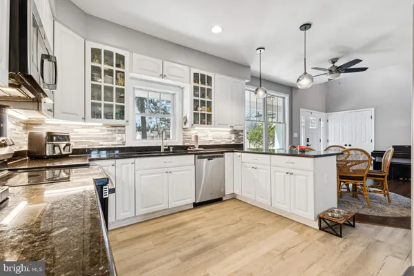 a kitchen with granite countertop a stove a sink a counter space wooden floor and cabinets
