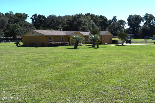 a front view of a house with a garden and trees