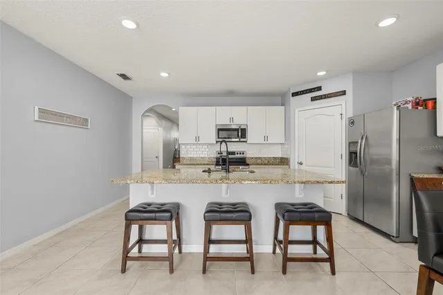 a kitchen with refrigerator and chairs