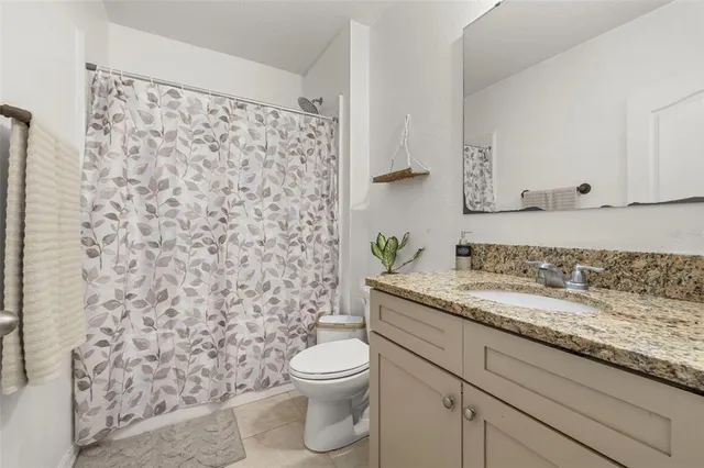 a bathroom with a granite countertop sink a toilet and a mirror