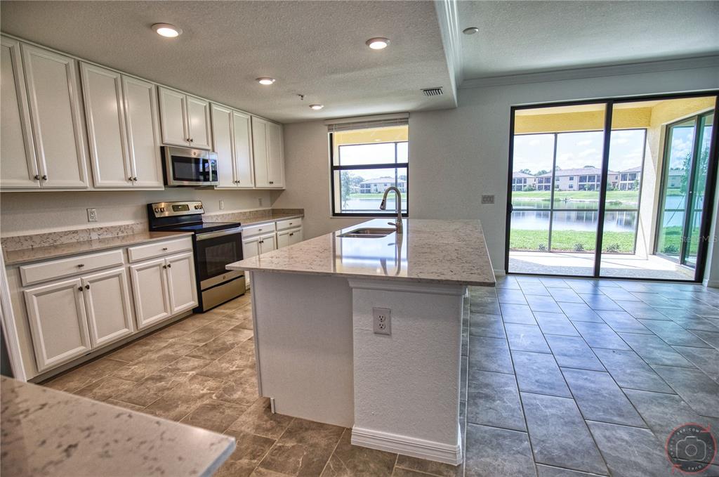 12355 Ghiberti Circle, Unit 101 Venice, FL 34293 - Photo 11 of 41 a kitchen with stainless steel appliances granite countertop a stove a sink and a microwave