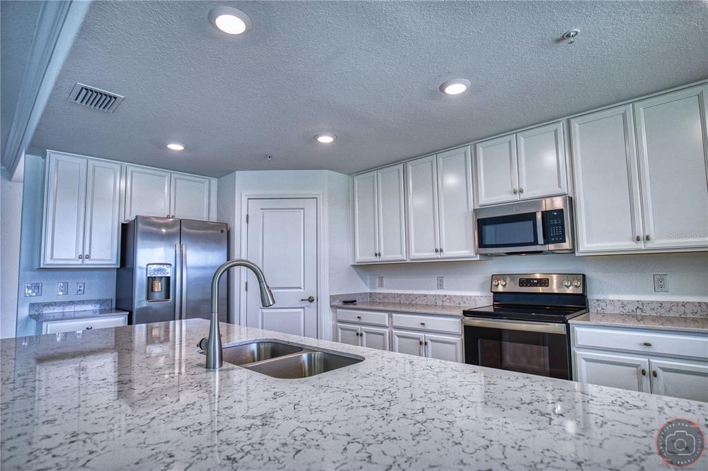 12355 Ghiberti Circle, Unit 101 Venice, FL 34293 - Photo 12 of 41 a kitchen with kitchen island granite countertop a sink stainless steel appliances and cabinets