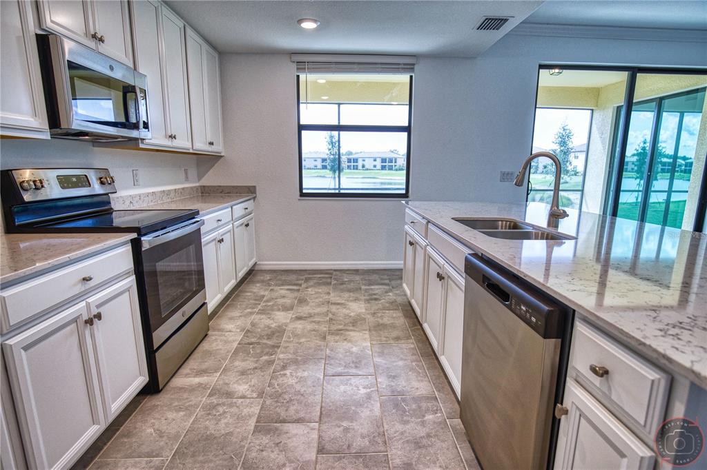 12355 Ghiberti Circle, Unit 101 Venice, FL 34293 - Photo 14 of 41 a kitchen with granite countertop a stove sink and cabinets