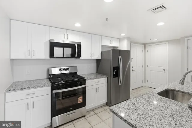 a living room with furniture a kitchen view and a refrigerator