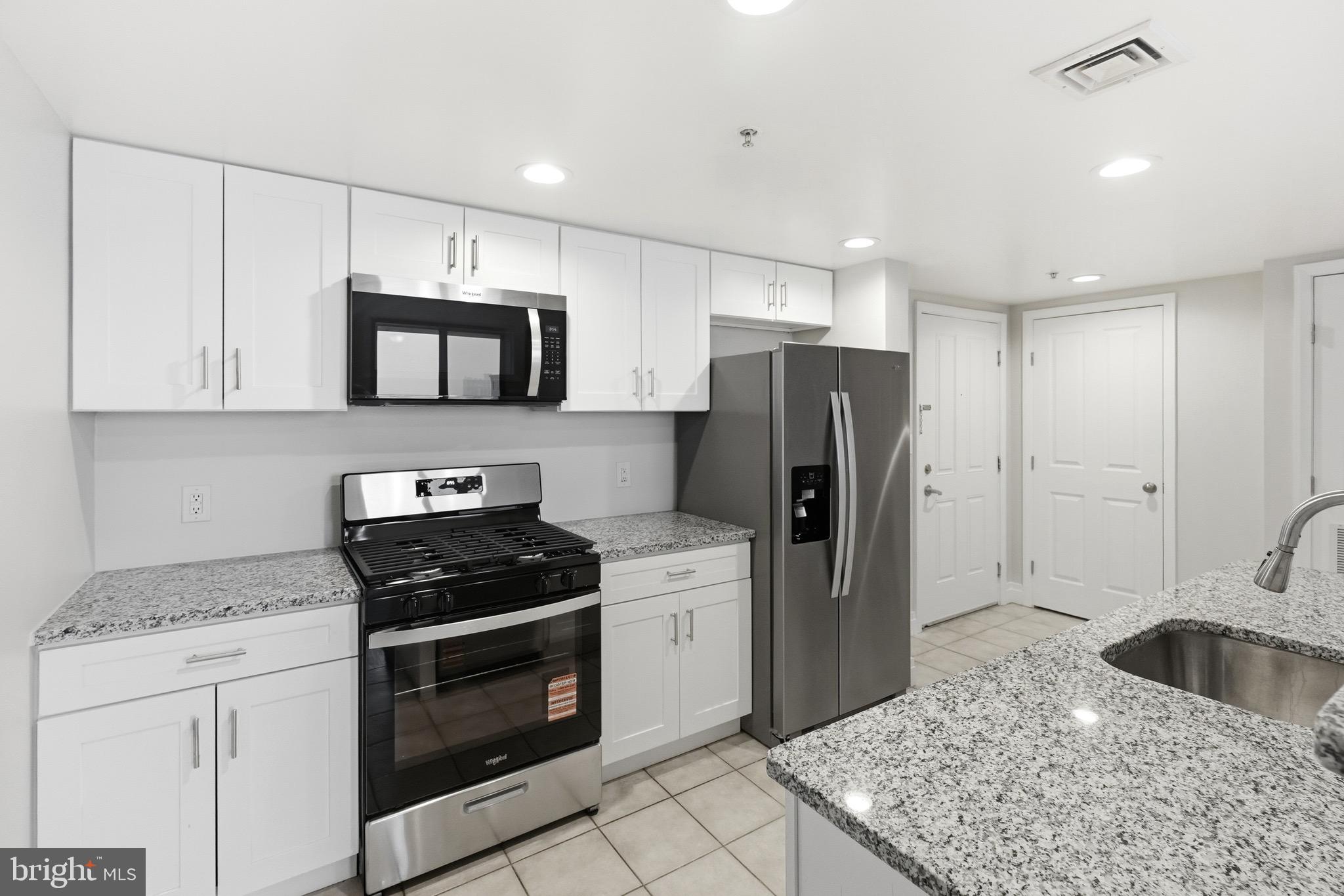 414 Water Street, Unit 1501 Baltimore, MD 21202 - Photo 10 of 21 a kitchen with stainless steel appliances granite countertop a stove a refrigerator and a microwave