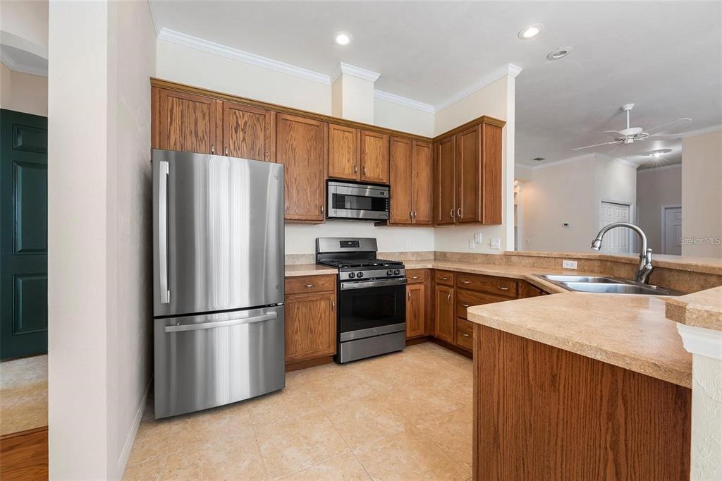 8668 Southwest 77th Avenue Gainesville, FL 32608 - Photo 11 of 29 a kitchen with stainless steel appliances granite countertop a refrigerator stove a sink and a microwave oven with wooden floor