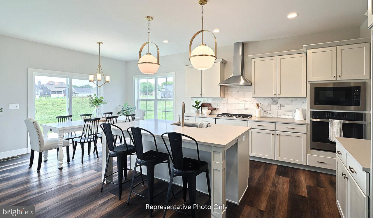 116 Washington Crossing York, PA 17404 - Photo 12 of 32 a kitchen with stainless steel appliances granite countertop a stove a sink a refrigerator a dining table and chairs with wooden floor
