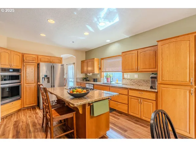 a kitchen with stainless steel appliances granite countertop a refrigerator a stove and a sink