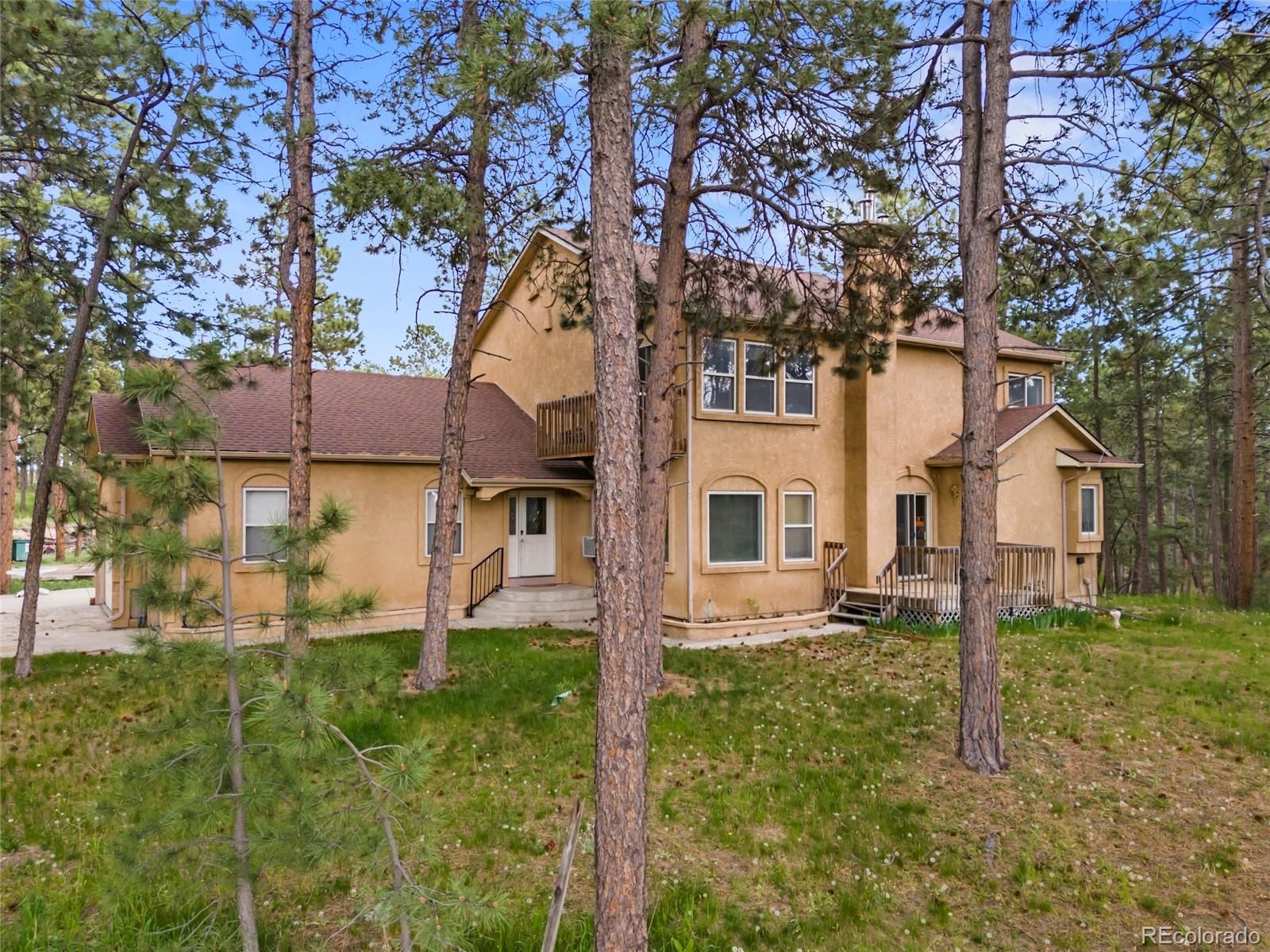 16575 Roller Coaster Road Colorado Springs, CO 80921 - Photo 1 of 26 a view of a yard in front of a house with plants and large tree