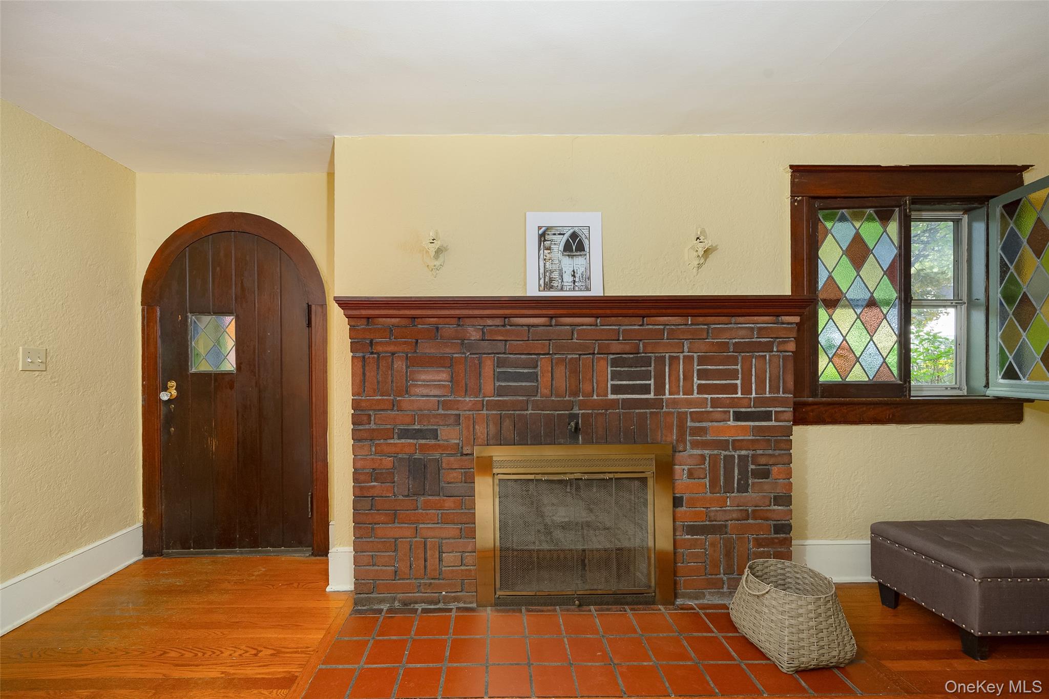 30 Marple Road Poughkeepsie, NY 12603 - Photo 9 of 26 Brick fireplace with a brass-toned screen, flanked by a stained glass window and an arched wood door with a decorative glass insert