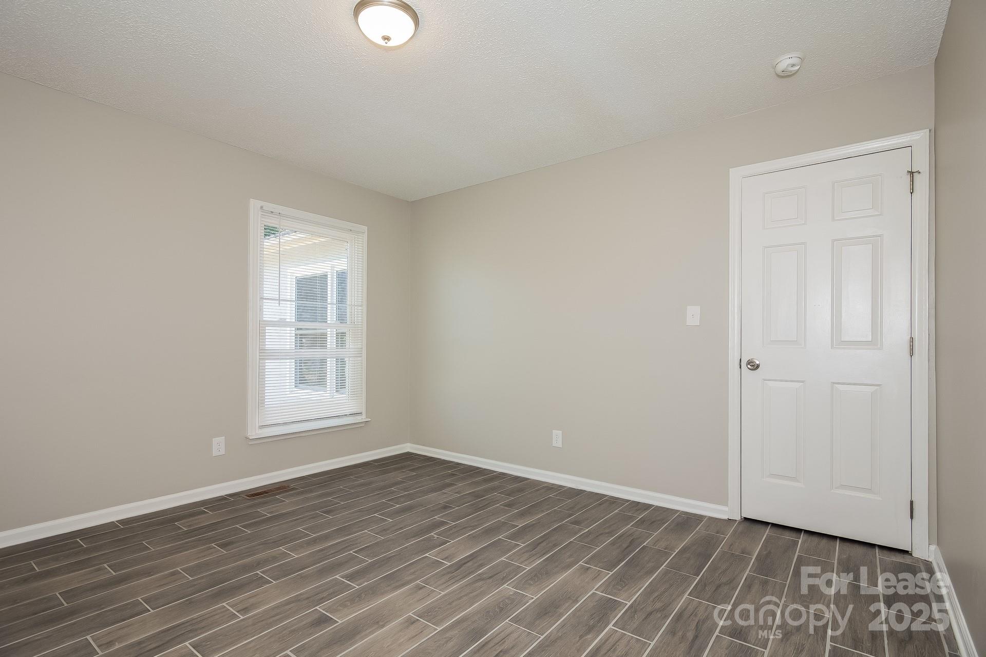 124 Shade Tree Court Gastonia, NC 28056 - Photo 12 of 16 an empty room with wooden floor and windows