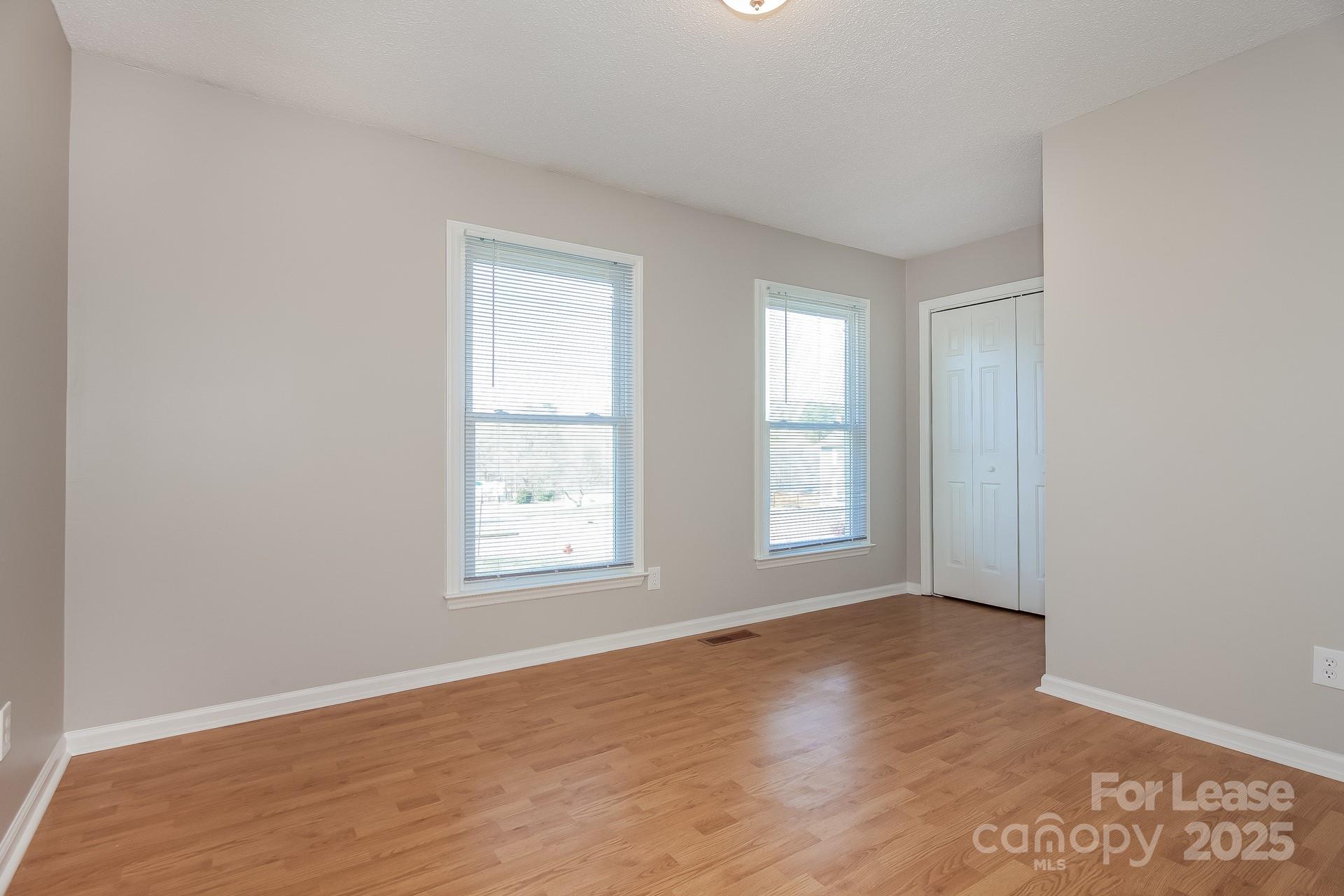 124 Shade Tree Court Gastonia, NC 28056 - Photo 10 of 16 an empty room with wooden floor and windows