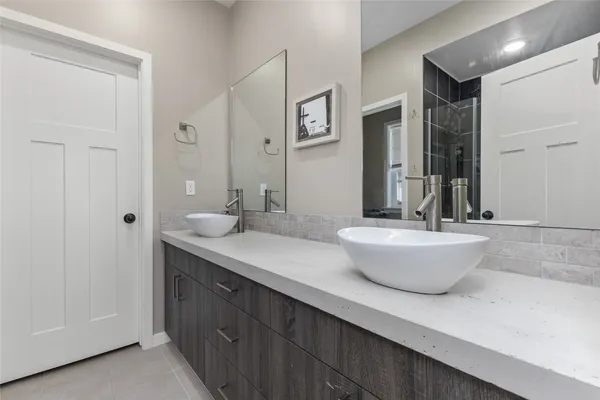 a bathroom with a granite countertop sink a toilet a large mirror and shower