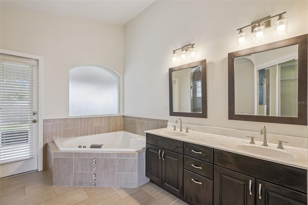 893 Watt Circle Deltona, FL 32738 - Photo 19 of 34 a bathroom with a tub a double vanity sink and mirror