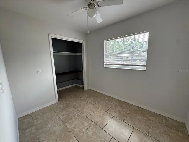 an empty room with a ceiling fan and a window