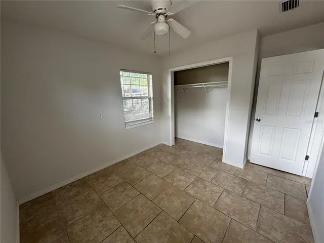 an empty room with a chandelier fan and windows