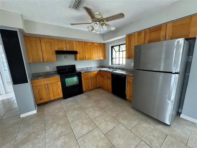 a kitchen with stainless steel appliances granite countertop a refrigerator a sink a stove top oven a counter space and cabinets