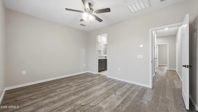 a view of empty room with wooden floor and ceiling fan
