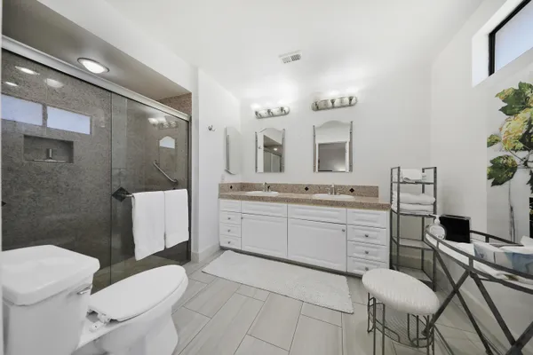 a bathroom with a granite countertop toilet sink and mirror