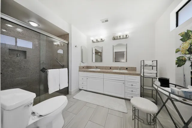 a bathroom with a granite countertop toilet sink and mirror