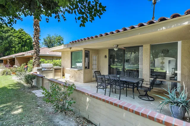 a view of a patio with table and chairs potted plants and large tree