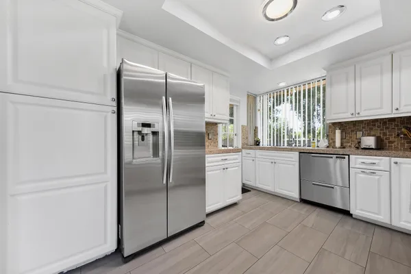 a kitchen with granite countertop white cabinets and stainless steel appliances