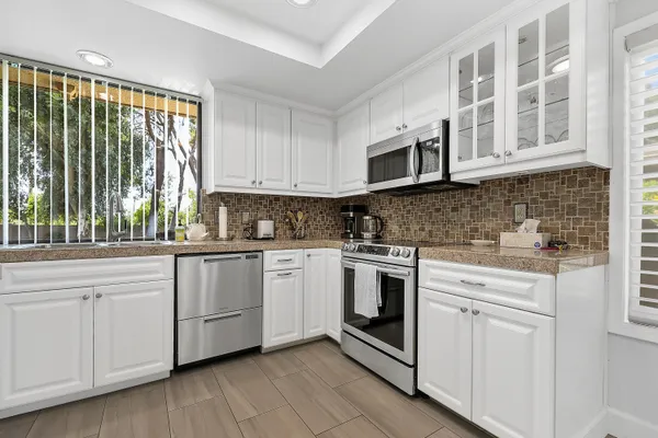a kitchen with cabinets stainless steel appliances a sink and wooden floor