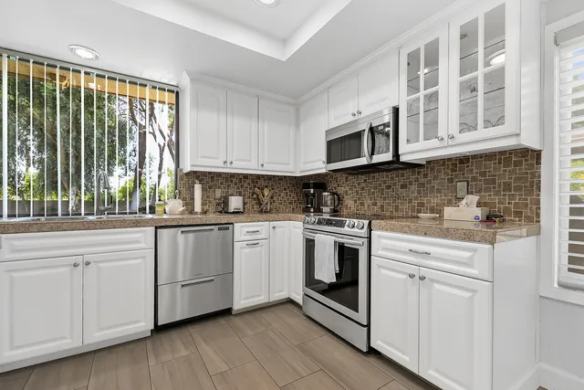 a kitchen with cabinets stainless steel appliances a sink and wooden floor