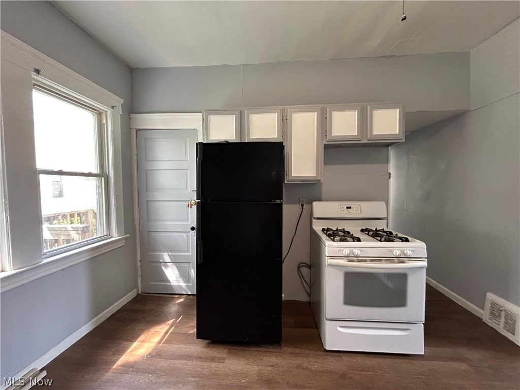 3403 Fulton Road, Unit DOWN Cleveland, OH 44109 - Photo 16 of 18 Kitchen featuring white range with gas stovetop, black refrigerator, dark hardwood / wood-style floors, and white cabinetry