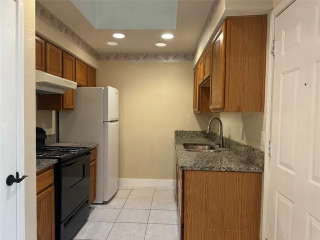 a kitchen with stainless steel appliances granite countertop a refrigerator a sink and a stove