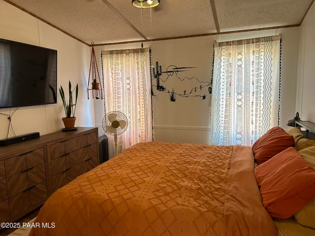 a bedroom with a bed and a flat tv screen on dresser