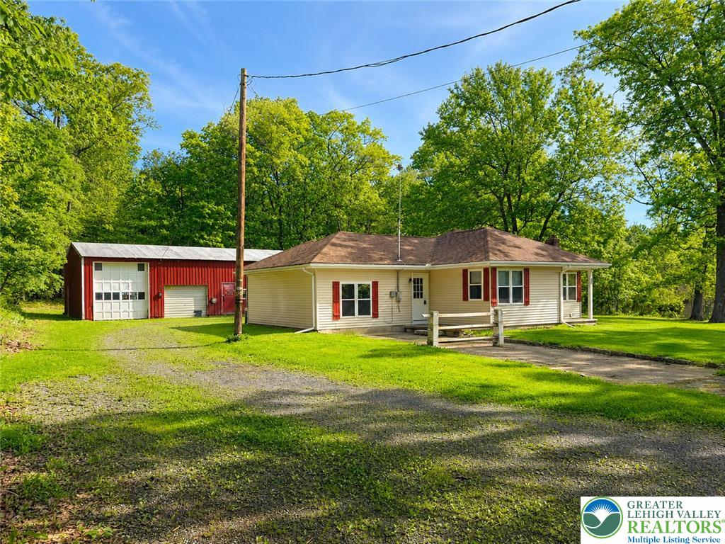 A charming residence with a detached garage nestled among vibrant, mature trees.
