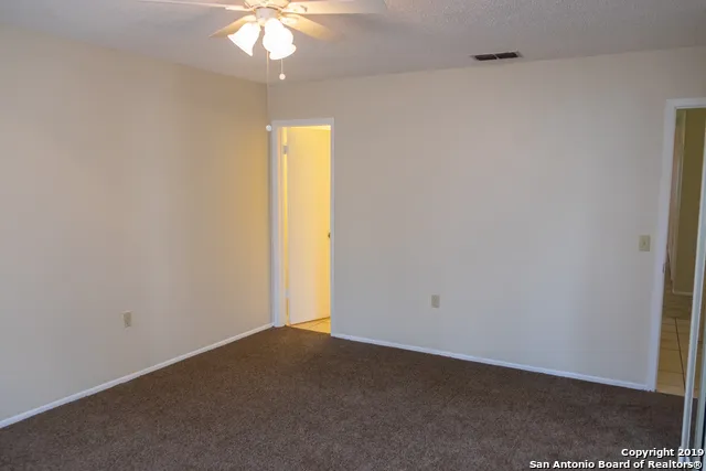 an empty room with a chandelier fan and a window