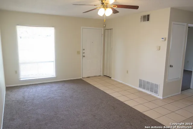 an empty room with a window and a chandelier fan