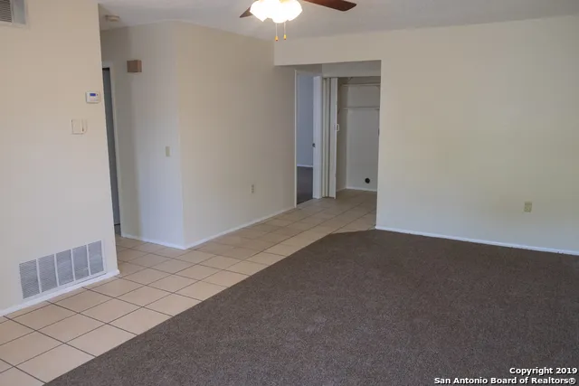 a view of a room with a ceiling fan and window