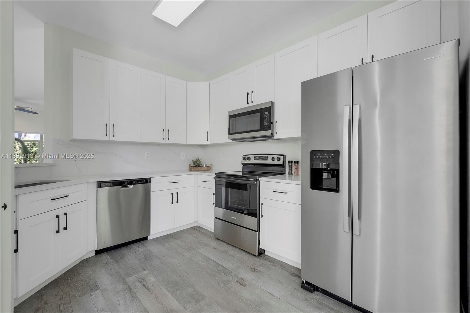 108 Lighthouse Circle, Unit E Tequesta, FL 33469 - Photo 5 of 34 a kitchen with cabinets stainless steel appliances and wooden floor