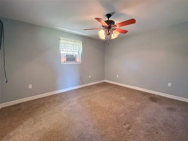 an empty room with a window and a fan