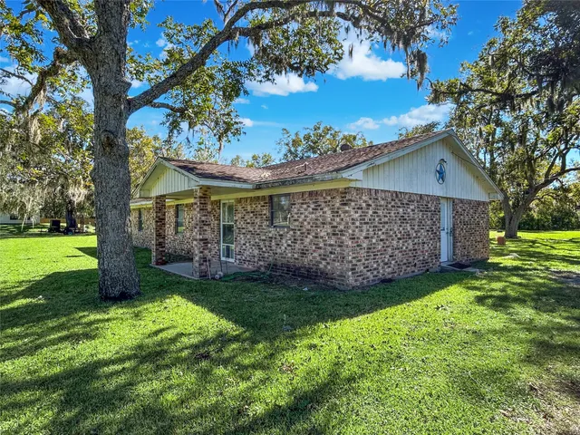 a view of a house with a yard and a large tree