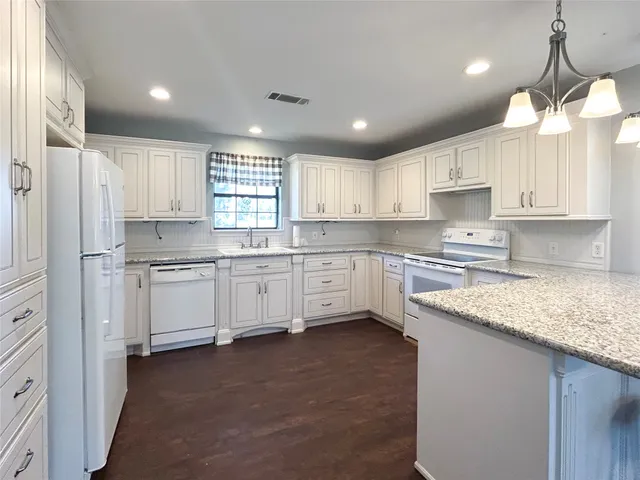a kitchen with granite countertop white cabinets sink and stainless steel appliances