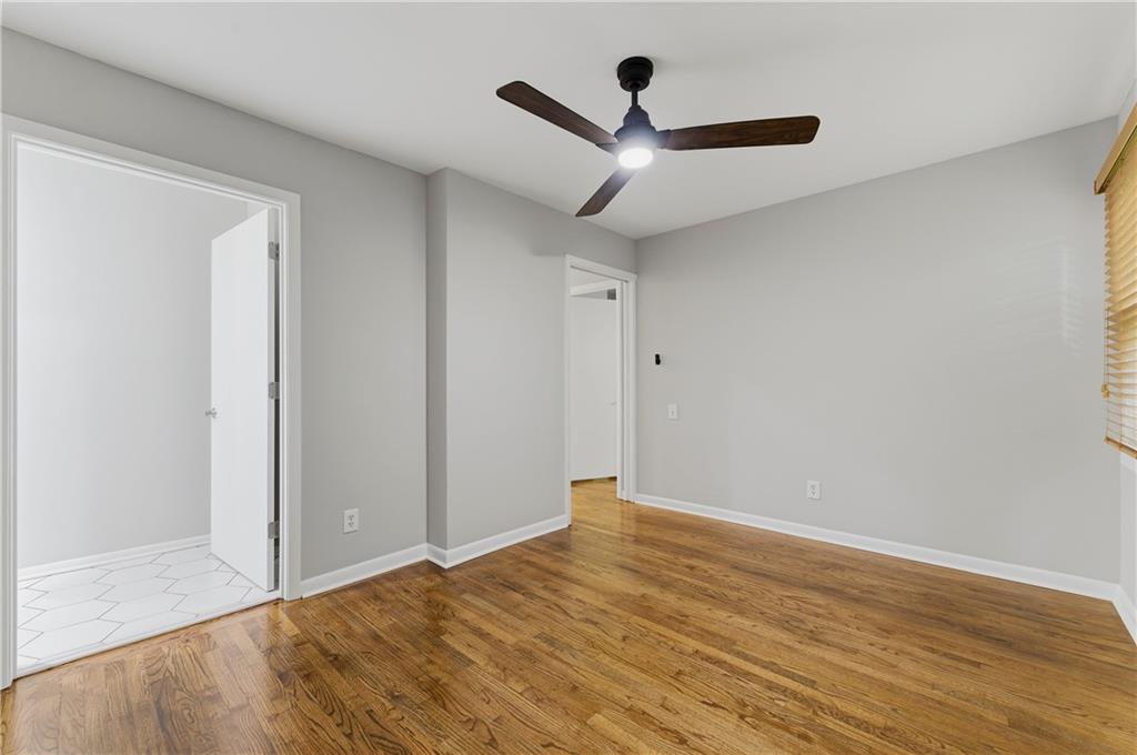 1063 Seville Drive Clarkston, GA 30021 - Photo 17 of 25 an empty room with wooden floor and ceiling fan