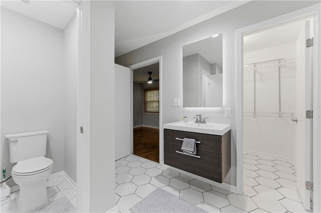 1063 Seville Drive Clarkston, GA 30021 - Photo 18 of 25 a bathroom with a granite countertop sink a toilet and a mirror