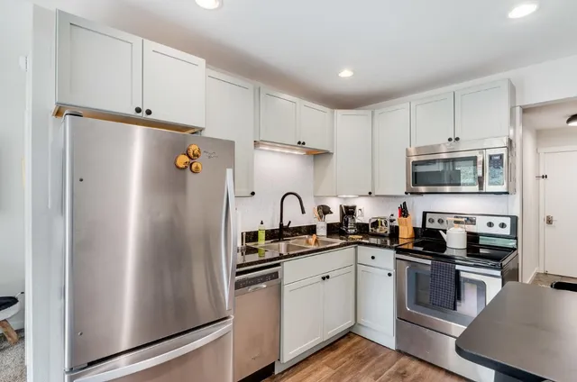 a kitchen with refrigerator a sink and white cabinets