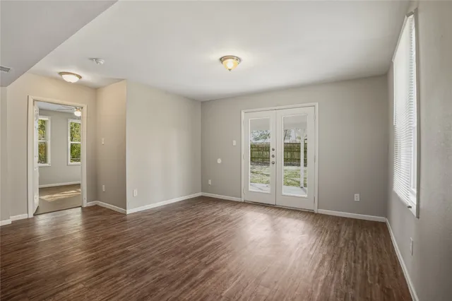 a view of an empty room with wooden floor and a window