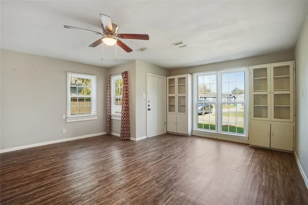 a view of empty room with wooden floor and fan