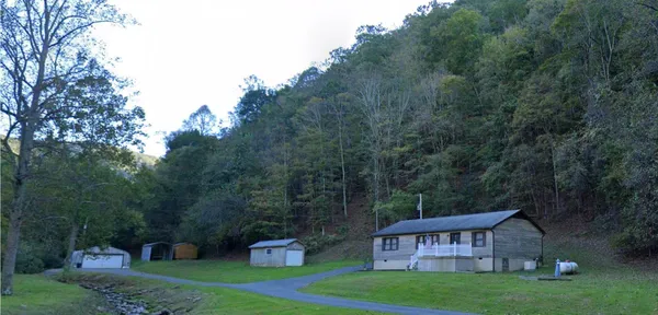 a view of a big house with a big yard and large trees